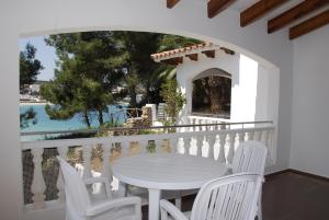 a white table and chairs on a balcony with a view of the water at Apartamentos Jardin Playa in Punta Grossa