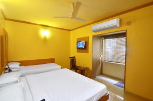a yellow room with two beds and a window at Hotel A P in Coimbatore