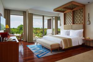 a bedroom with a large bed and a balcony at MERUSAKA Nusa Dua in Nusa Dua