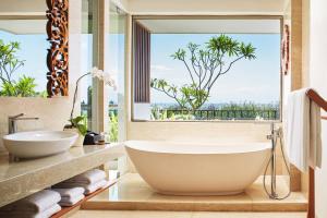 a bathroom with a tub and a large window at MERUSAKA Nusa Dua in Nusa Dua