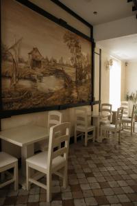una habitación con mesas y sillas y un cuadro en la pared en Georg Palace Hotel, en Chernivtsi