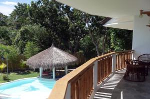 a swimming pool with a straw umbrella on a deck at Bohol Dreamcatcher Resort in Panglao Island