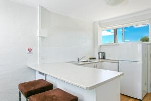 a white kitchen with a counter and two stools at Alloggio Bathurst in Bathurst