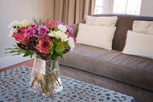 un jarrón de flores en una mesa delante de un sofá en First Avenue Guesthouse, en Port Elizabeth