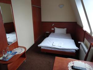 mały pokój z łóżkiem i lustrem w obiekcie Hotel Wielkopolanka w mieście Środa Wielkopolska