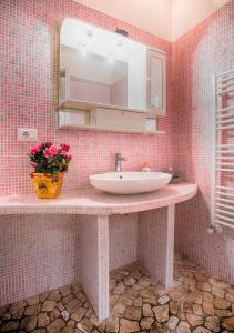 un bagno piastrellato rosa con lavandino e specchio di The Jujube Flower a Viterbo