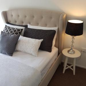 a bed with pillows and a table with a lamp at Belle in Bowral in Bowral