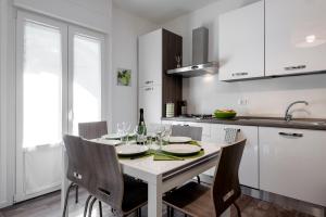una cocina blanca con una mesa con copas de vino en StayEasy Filzi11 - 3 Bedrooms, 2 baths - Central Station, en Milán