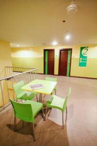 Go Hotels Dumaguete في دوماغيتي: غرفة مع طاولة وكراسي خضراء