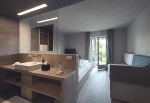 un bagno con un lavandino, un letto e uno specchio di Das Wanda a Caldaro