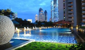 a large swimming pool with a city skyline in the background at The Sultan Residences Jakarta in Jakarta