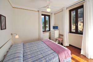 a bedroom with a bed and a desk and windows at Casabb in Toscolano Maderno