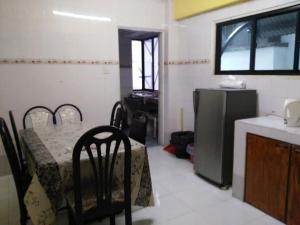 a room with a table and a kitchen with a refrigerator at SA Apartments @ Desa Anthurium in Cameron Highlands