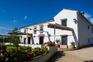 una casa blanca con flores rojas delante en Casa Rural Finca Buytrón, en Montilla