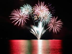 a group of fireworks exploding in the sky over the water at Toya Kohan Tei in Lake Toya