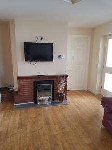 a living room with a fireplace and a flat screen tv at Ingoldale House in Ingoldmells