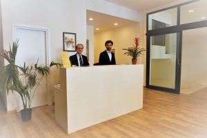 deux hommes debout à un comptoir de réception dans un bureau dans l'établissement B&B I Tetti di Siena, à Sienne