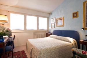 a bedroom with a bed and a table and two windows at Villa Bellaria B&B in Alseno