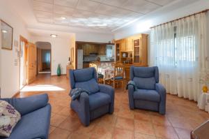 a living room with two blue chairs and a kitchen at Portilet in La Drova