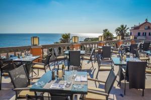 a restaurant with tables and chairs and the ocean at Grande Real Villa Itália Hotel & Spa in Cascais