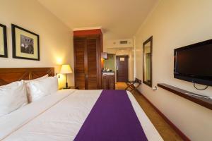 a bedroom with a large bed and a flat screen tv at Ole Sereni in Nairobi