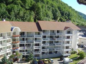 ein Apartmenthaus mit Autos auf einem Parkplatz in der Unterkunft Terres de France - Résidence les Silènes in Allevard