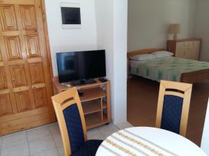 Kleines Zimmer mit einem TV, einem Tisch und Stühlen. in der Unterkunft Apartments Ćenan in Korčula