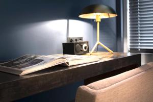 a desk with a book and a lamp and a lamp at COMMUNE suites in Amsterdam
