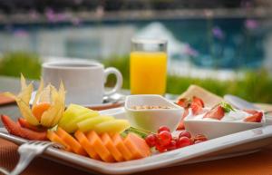 a plate of fruit and vegetables on a table with a glass of orange juice at Grande Real Villa Itália Hotel & Spa in Cascais