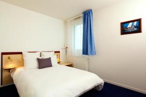 Un dormitorio con una gran cama blanca y una ventana en Appart'City Classic Rennes Beauregard en Rennes