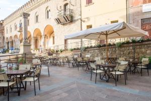 an outdoor patio with tables and chairs and an umbrella at Albergo Colonna in Bertinoro