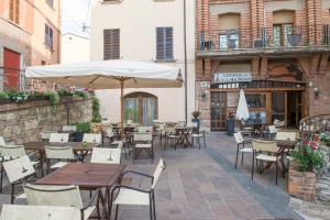 un patio esterno con tavoli, sedie e ombrellone di Albergo Colonna a Bertinoro