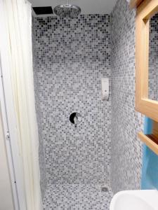 a bathroom with a shower with gray tiles at Nunia Inn Bandara Jakarta in Tangerang