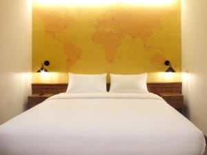a bedroom with a white bed with a yellow wall at Nunia Inn Bandara Jakarta in Tangerang