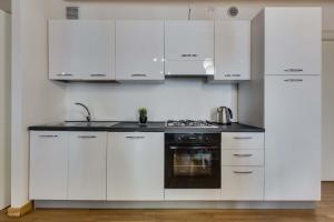 Biała kuchnia z białymi szafkami i zlewem w obiekcie Appartamento Arco w Padwie