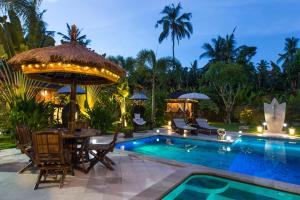 a resort with a pool and a table and chairs at Villa Gusmania in Candidasa