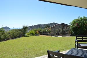 a patio with a lawn with chairs and a view of the ocean at Sa Tirìa in Chia