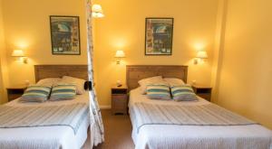 two beds in a room with yellow walls at LOGIS Hôtel & Restaurant - Au Bord du Lac in Saint-Rémy-lès-Chevreuse