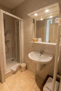 a bathroom with a sink and a shower at LOGIS Hôtel & Restaurant - Au Bord du Lac in Saint-Rémy-lès-Chevreuse