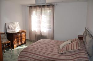 ein Schlafzimmer mit einem Bett, einer Kommode und einem Fenster in der Unterkunft Luc et Corine in Saint-Restitut