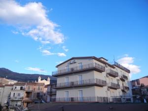 un edificio alto de color blanco con balcones encima en Albergo Il Brillantino, en San Nicola Arcella