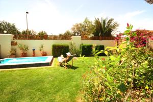 Una donna seduta su una sedia in un giardino vicino a una piscina di Octopus Apartment - Lagoon Villa a Dahab