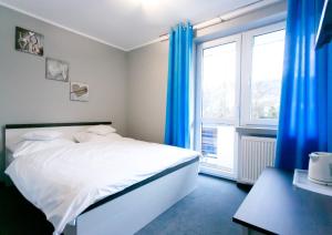 a bedroom with a white bed and blue curtains at Pokoje Beskid Brenna in Brenna