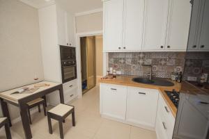 - une cuisine avec des placards blancs, un évier et une table dans l'établissement Apartment Lumen, à Kharkov 4 autres photos