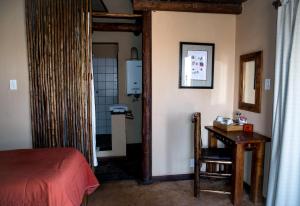 a bedroom with a bed and a table and a door at Xaus Lodge in Twee Rivieren