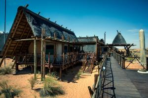 a building with a thatched roof in the desert at Xaus Lodge in Twee Rivieren
