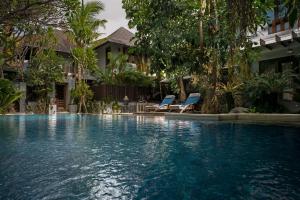 a swimming pool in front of a house with two chairs at D'Sriwing Villa Gallery in Kuta