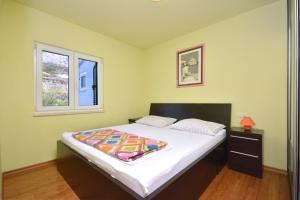 a bedroom with a bed and two windows at Beach Apartman Petra in Podstrana