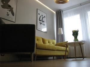 - un salon avec un canapé jaune et une table dans l'établissement Apartament Relax Gdynia, à Gdynia