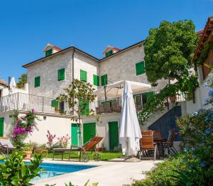 a building with an umbrella and a swimming pool at Villa Celine in Postira